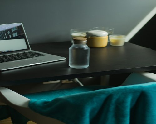 An organized workspace table featuring a laptop, a warm desk lamp, and a glass of refreshing water