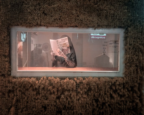 A relaxed person reading a physical magazine next to a window during an afternoon downpour in Medellin
