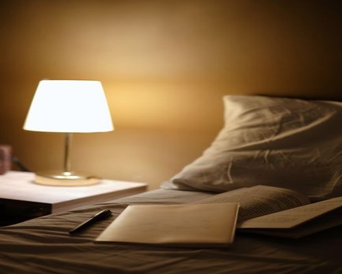 An open book illuminated by a gentle warm light from a bedside lamp in a cozy twilight room atmosphere
